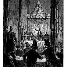 view of a conference hall showing a cheering audience seen from behind and a speaker on a platform